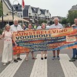 Zes leden van Cultuur Verheft met het spandoek van Kunstbeleving Voorhout op een zebrapad in de Herenstraat.
